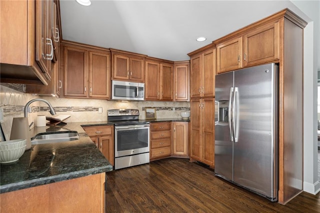 kitchen with tasteful backsplash, sink, dark stone countertops, stainless steel appliances, and dark wood-type flooring