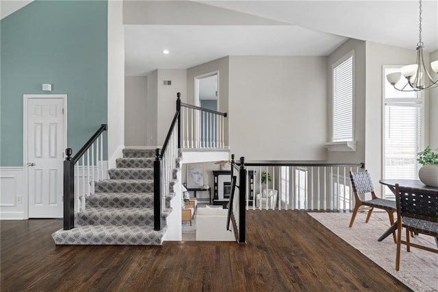 stairway featuring high vaulted ceiling, hardwood / wood-style floors, and a notable chandelier