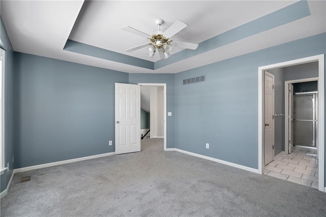 unfurnished bedroom with ceiling fan, light colored carpet, and a raised ceiling