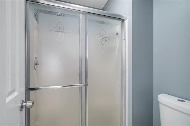 bathroom featuring toilet and a shower with shower door