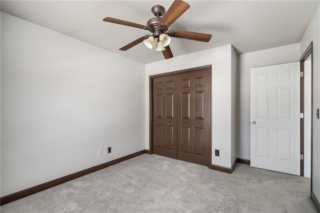 unfurnished bedroom with ceiling fan, light colored carpet, and a closet