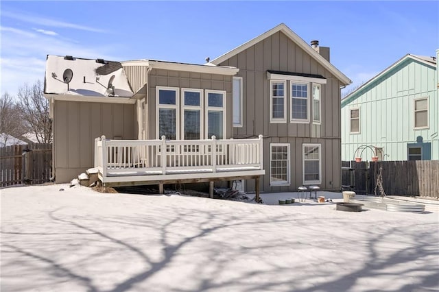 snow covered back of property featuring a wooden deck