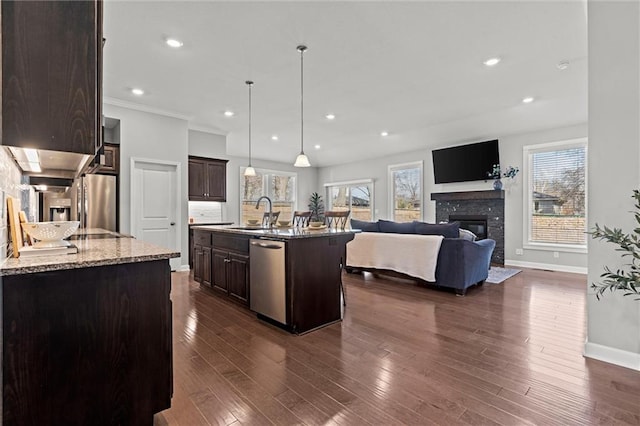 kitchen with dark wood-style floors, stainless steel dishwasher, open floor plan, a sink, and dark brown cabinets