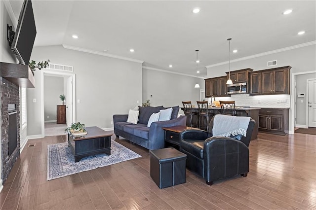 living room featuring a glass covered fireplace, visible vents, and wood finished floors