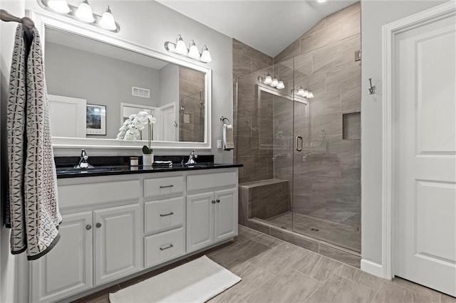 bathroom with a shower stall, visible vents, vaulted ceiling, and vanity