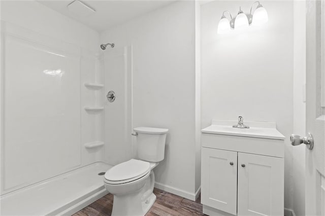 bathroom featuring toilet, wood finished floors, vanity, baseboards, and a shower