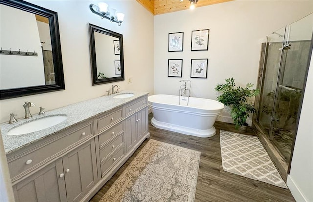 full bathroom featuring a stall shower, a soaking tub, a sink, and wood finished floors