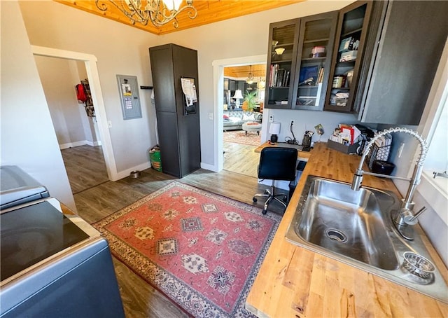 office area featuring electric panel, baseboards, wood finished floors, an inviting chandelier, and a sink