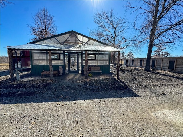 view of front of home with an outbuilding, metal roof, and a greenhouse