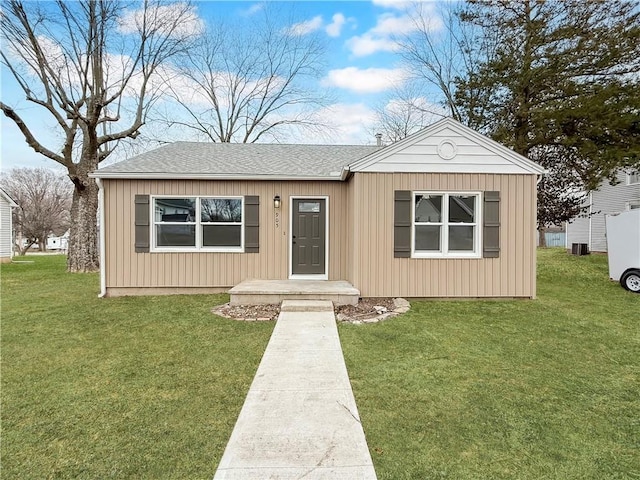 view of front of house with a front lawn, central AC unit, board and batten siding, and a shingled roof