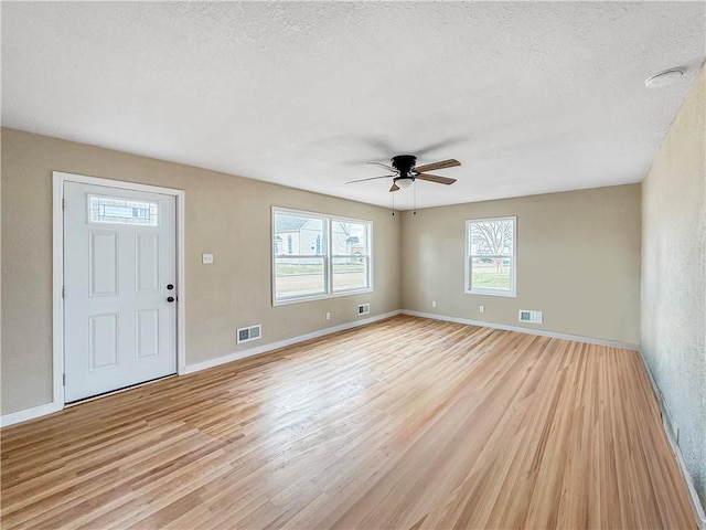 interior space featuring visible vents, a textured ceiling, a ceiling fan, and light wood finished floors