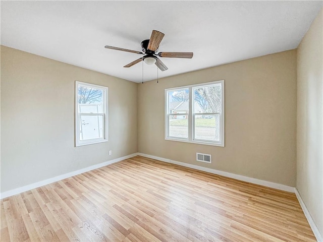 spare room featuring plenty of natural light, visible vents, light wood-type flooring, and baseboards