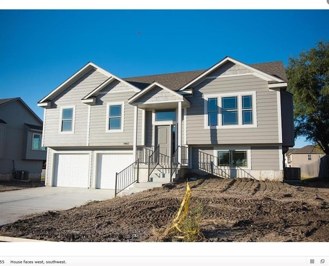 raised ranch featuring a garage and cooling unit