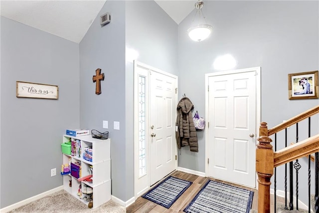 entryway featuring lofted ceiling, stairs, baseboards, and wood finished floors