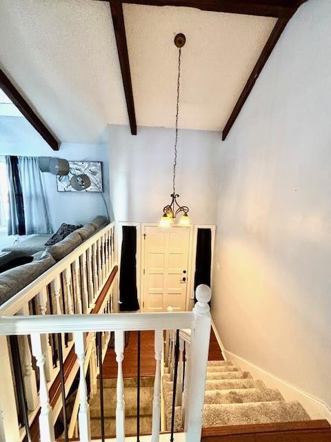 stairway featuring a textured ceiling and beamed ceiling