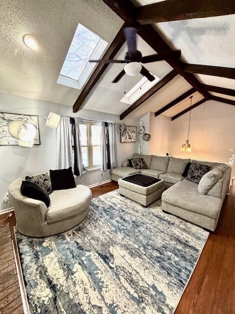 living room with lofted ceiling with skylight, dark hardwood / wood-style floors, ceiling fan, and a textured ceiling