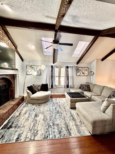 living room with ceiling fan, lofted ceiling with skylight, a fireplace, wood-type flooring, and a textured ceiling