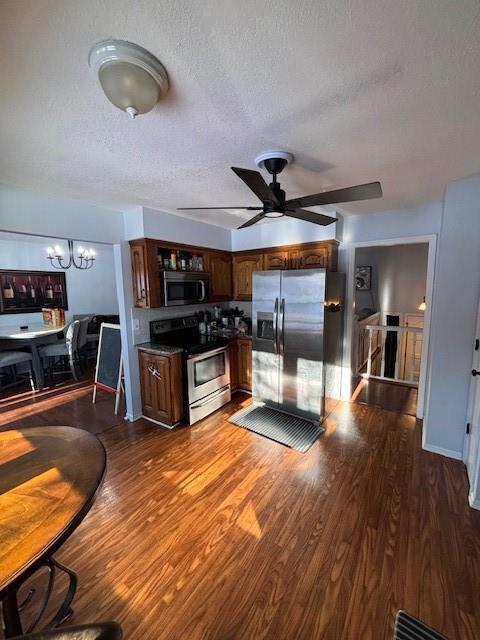 kitchen featuring dark hardwood / wood-style flooring, ceiling fan with notable chandelier, a textured ceiling, and appliances with stainless steel finishes