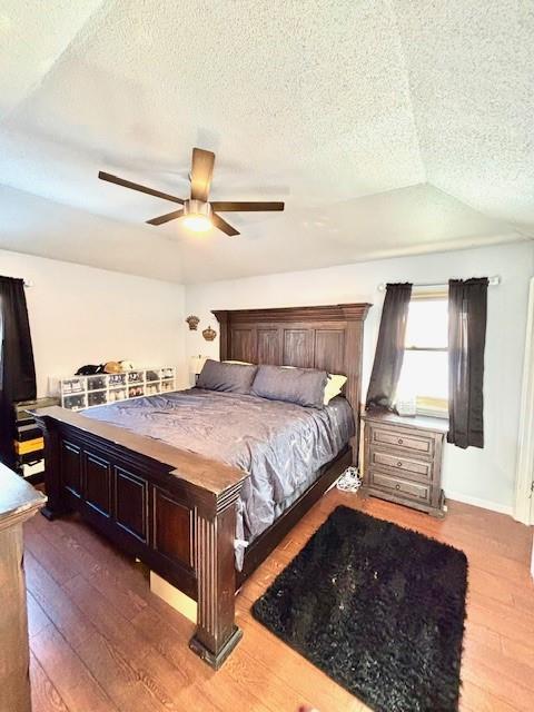 bedroom with dark hardwood / wood-style flooring, ceiling fan, and a textured ceiling