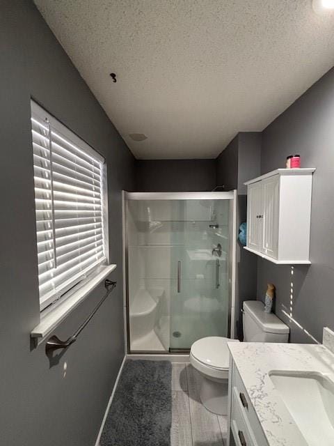 bathroom featuring vanity, a shower with shower door, a textured ceiling, and toilet