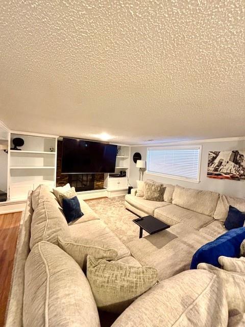 living room with hardwood / wood-style floors, built in features, and a textured ceiling