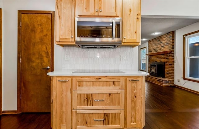 kitchen featuring dark wood-style floors, stainless steel microwave, black electric stovetop, and decorative backsplash