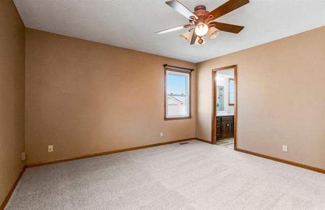 spare room featuring visible vents, light colored carpet, baseboards, and ceiling fan