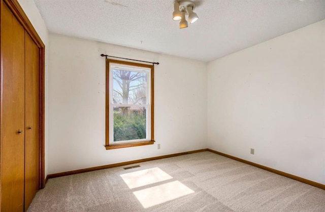 unfurnished bedroom with visible vents, carpet floors, a textured ceiling, and baseboards