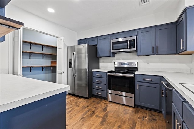 kitchen with blue cabinets, appliances with stainless steel finishes, and dark hardwood / wood-style floors