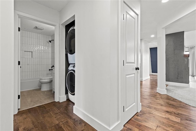 interior space with stacked washer and dryer and dark wood-type flooring