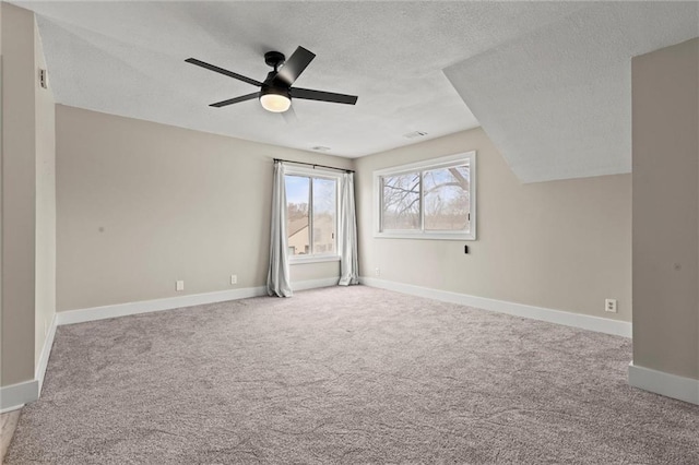 spare room with ceiling fan, light colored carpet, and a textured ceiling