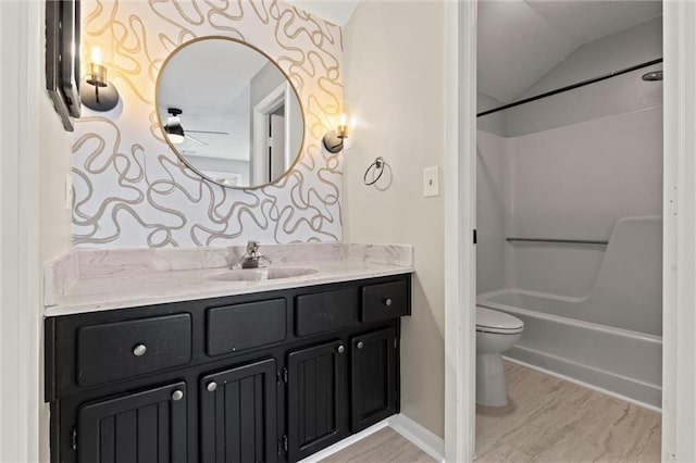 full bathroom with lofted ceiling, hardwood / wood-style flooring, vanity,  shower combination, and toilet