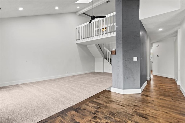 unfurnished living room featuring beamed ceiling, a skylight, high vaulted ceiling, hardwood / wood-style flooring, and ceiling fan