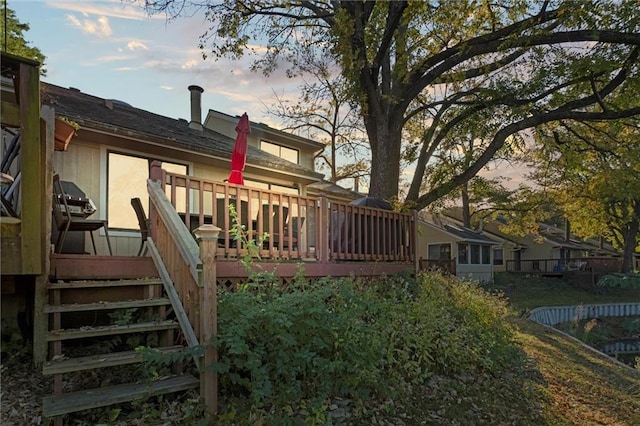 back house at dusk featuring a wooden deck