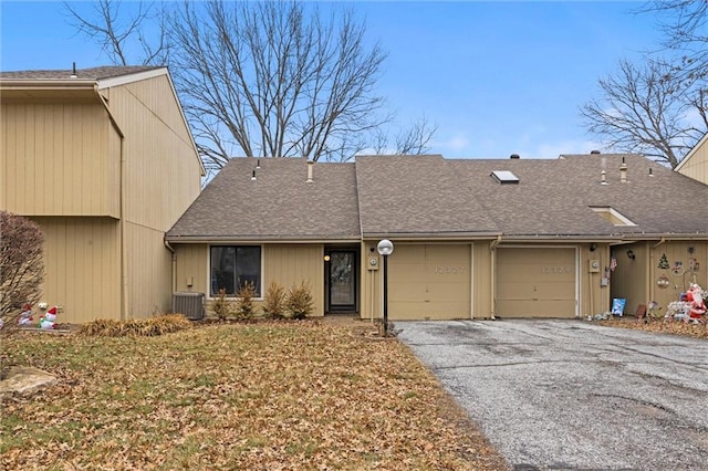 view of front of house with aphalt driveway, a garage, cooling unit, and a shingled roof