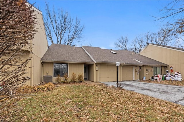 view of front of home featuring a shingled roof, aphalt driveway, a front yard, cooling unit, and an attached garage