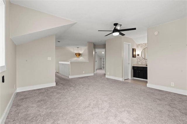 unfurnished living room with light carpet, baseboards, a ceiling fan, and vaulted ceiling