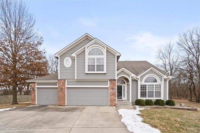 view of front of home with driveway, a shingled roof, an attached garage, a front lawn, and brick siding