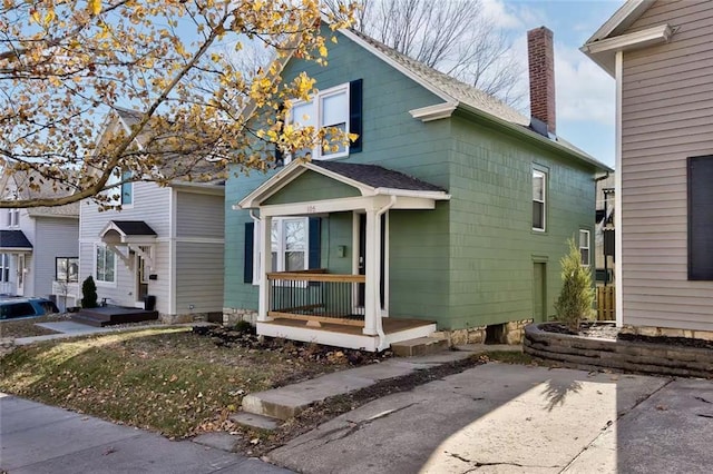 view of front of property with roof with shingles, a chimney, and a patio