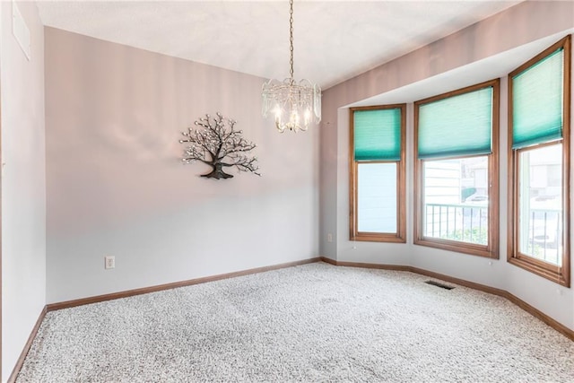 spare room with visible vents, baseboards, an inviting chandelier, and carpet flooring