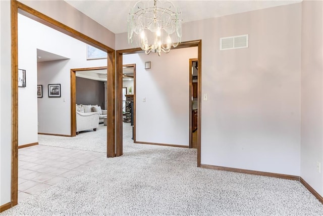 spare room with visible vents, baseboards, light colored carpet, and a chandelier