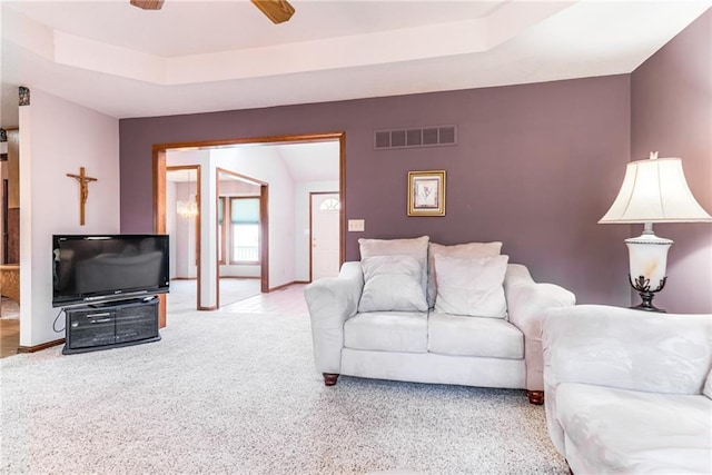 carpeted living area featuring visible vents, ceiling fan, baseboards, and a tray ceiling