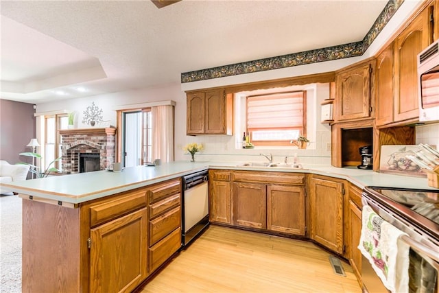 kitchen featuring dishwasher, stainless steel range with electric stovetop, a fireplace, a peninsula, and a sink