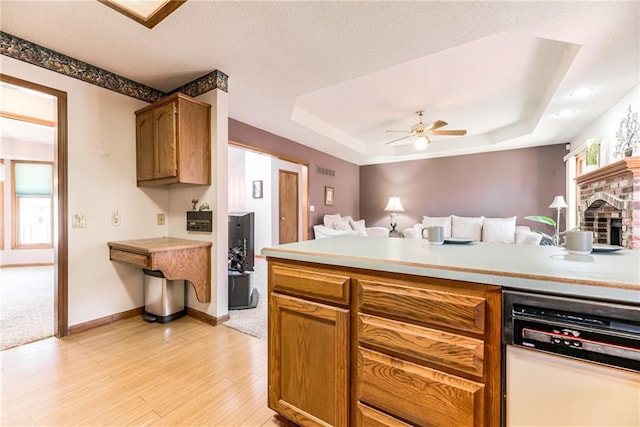 kitchen with dishwashing machine, ceiling fan, light countertops, a raised ceiling, and open floor plan