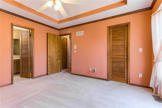 unfurnished bedroom featuring visible vents, a raised ceiling, and ornamental molding