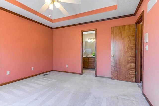 unfurnished bedroom featuring crown molding, a raised ceiling, baseboards, and carpet floors