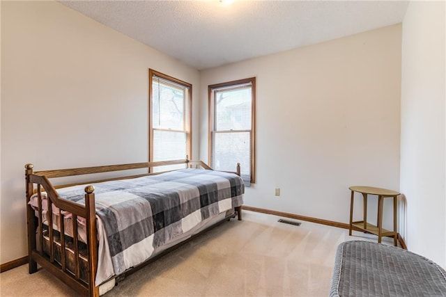 bedroom featuring a textured ceiling, light colored carpet, visible vents, and baseboards