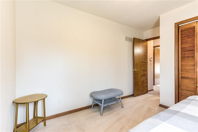 bedroom featuring visible vents, light carpet, a textured ceiling, a closet, and baseboards