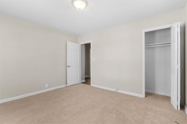 unfurnished bedroom with light colored carpet and a closet