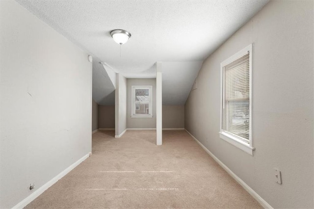 bonus room with light colored carpet, vaulted ceiling, and a textured ceiling